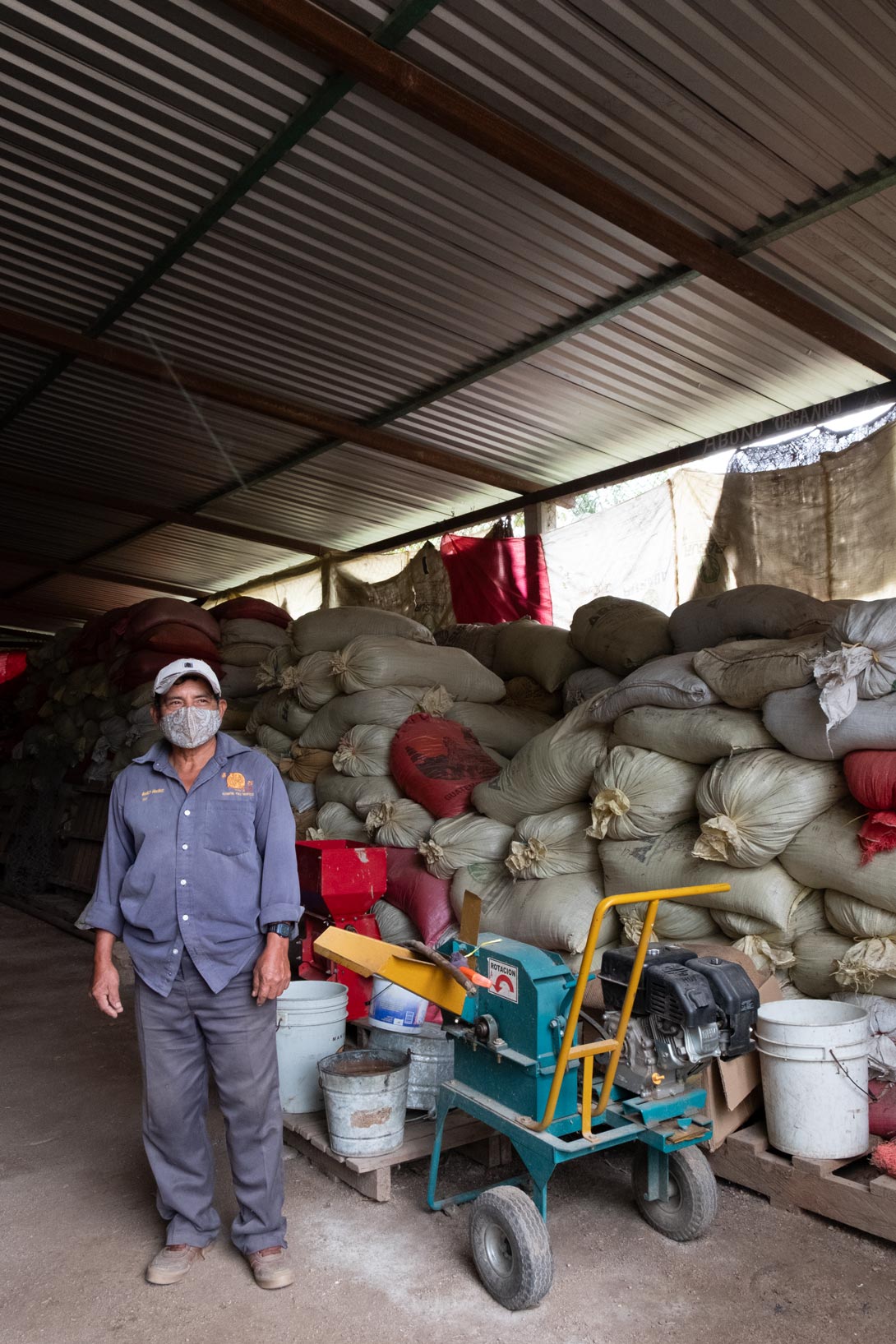 Ein Kaffeebauer von PMC in Mexiko steht vor Säcken mit Kaffeebohnen.
