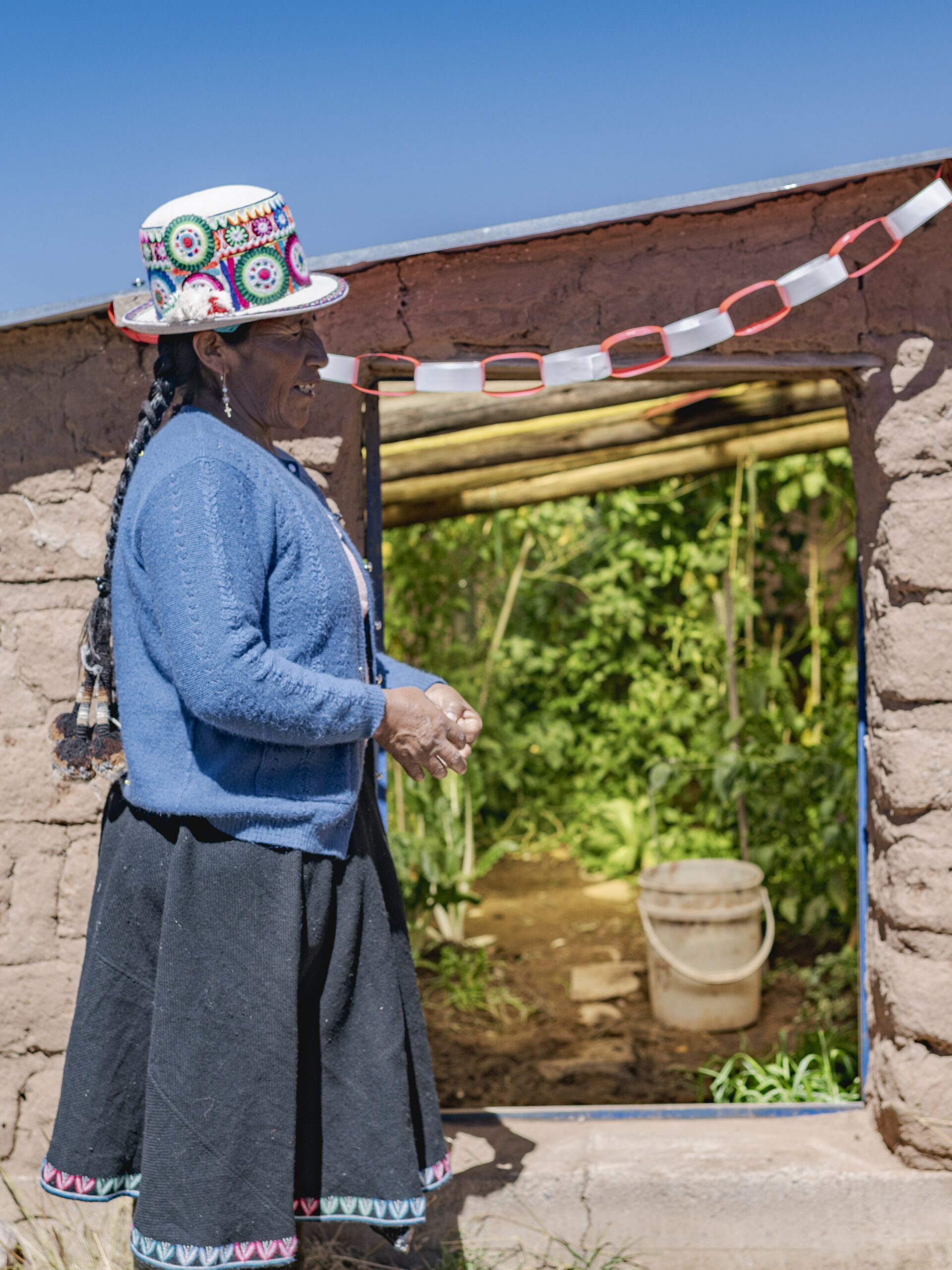 Eine Teilnehmerin von IDECA in Peru steht vor dem Gewächshaus.