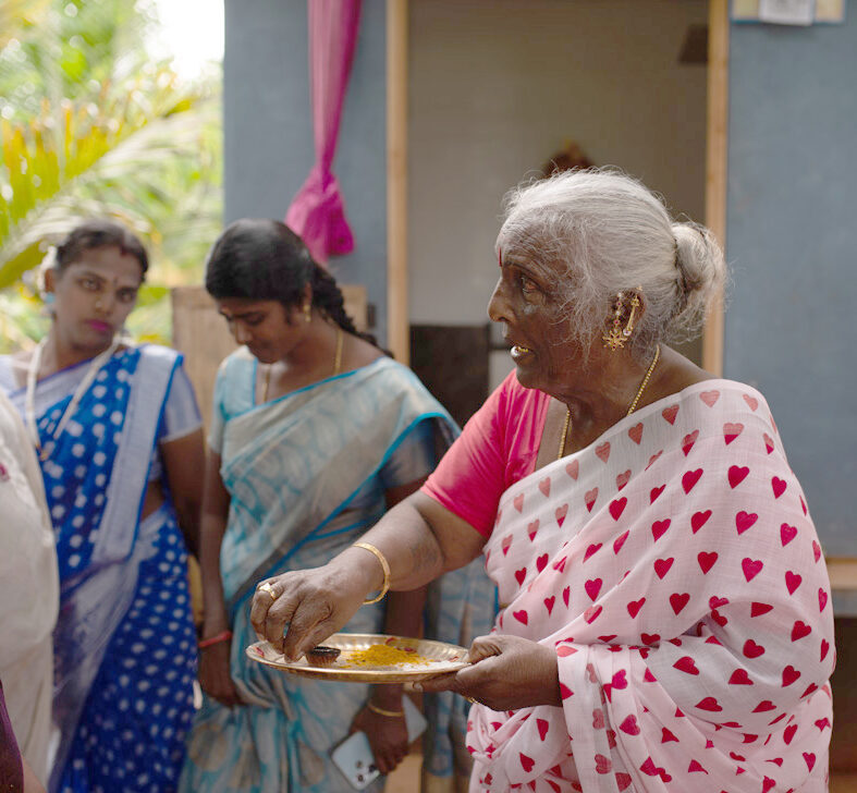 Die Projektleiterin Hashima Nayak von COROAT in Indien hält einen Teller mit Farbe in der Hand
